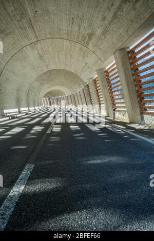 Lichtstreifen auf schwarzem Asphalt in einem Tunnel in Österreich Stockfoto