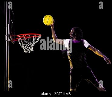 Ein reifer afrikanischer Basketballspieler Mann im Studio Mehrfachbelichtung im Studio isoliert auf schwarzem Hintergrund Stockfoto