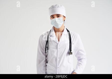 Portrait der jungen Ärztin trägt schützende medizinische Gesichtsmaske auf weißem Hintergrund, Kopierraum Stockfoto