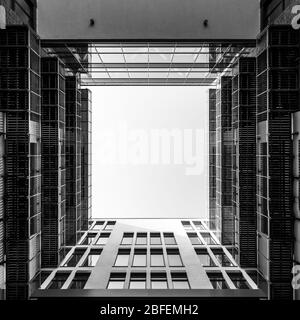 Innenhof des modernen Bürogebäudes Blick nach oben durch quadratische Öffnung in den Himmel in schwarz und weiß Stockfoto