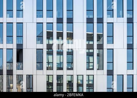 Modernes Bürogebäude, das sich in einer Fassade aus Edelstahl und Spiegelglasfenstern widerspiegelt Stockfoto