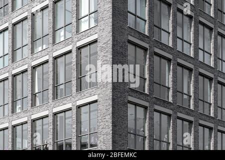 Moderne Fassade des Bürogebäudes mit dunklen Ziegelsteinen und hohen Fenstern Stockfoto