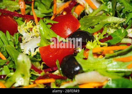 Gemüsesalat Tomaten, Möhren, Rüben, Salat, Rucola und Oliven in Scheiben geschnitten. Nahaufnahme des Hintergrundbilds Stockfoto