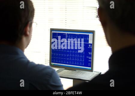 Ärzte überprüfen auf einem Computermonitor eine Elektrokardiogramm-Aufzeichnung des Herzzyklus eines Patienten, die von einem Elektrokardiographen erstellt wurde Stockfoto