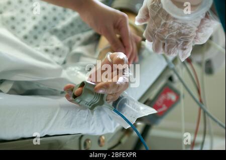 Ein Pflegepersonal legt ein Oximeter (Blut-Sauerstoff-Messgerät) an, mit dem die Pulsfrequenz und die Sauerstoffkonzentration des Blutes eines Patienten gemessen werden. Stockfoto