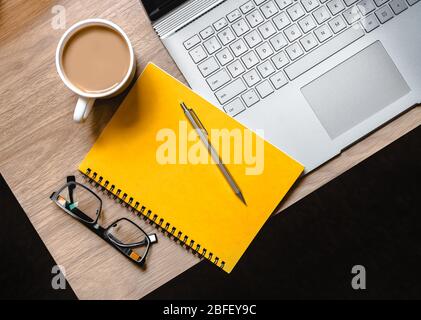 WFH - Work from Home Flatlay Foto vom Schreibtisch mit Laptop, Notizblock, Brille und Tasse Tee Stockfoto