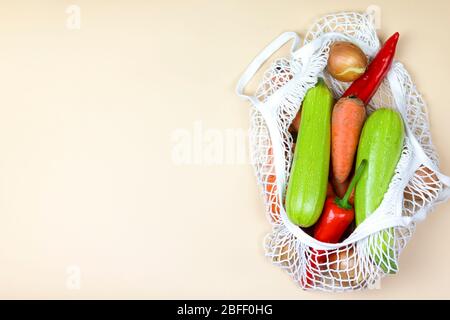 Farbiges Gemüse in einer Koton String Einkaufstasche auf neutralem beigefarbenem Hintergrund. Eco Zero Waste Konzept. Plastikfrei Stockfoto