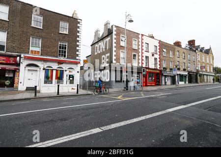 Dublin, Irland. 18. April 2020. Covid-19 Pandemie (Coronavirus). 22. Tag Sperrung. Ein Radfahrer kommt an einer Reihe geschlossener Geschäfte, Cafés, Pubs und einem Wandgemälde mit den Worten Don’t Be Afraid vorbei, auf der Richmond Street South in Dublin, als Irland in die dritte Woche der Lockdown eintritt. Foto: Sam Boal/Rollingnews.ie Stockfoto