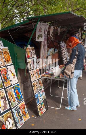 Frau mit orangefarbenen Haaren beim Stöbern in den Bouquinistes von Paris (Pariser Bücherstände), am linken Ufer der seine in Paris - Genenale Szenen von paris Stockfoto