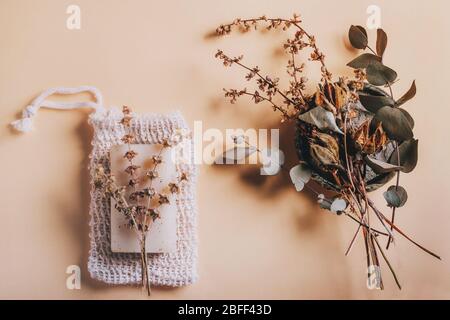 Peeling-Seife auf Massagesäcke mit trockenen Blumen und Kräutern. Natürliches Spa- und Hautpflegekonzept zur Schönheitsreinigung. Flaches Lay-Muster mit kupferem Raum in der Mitte. Stockfoto