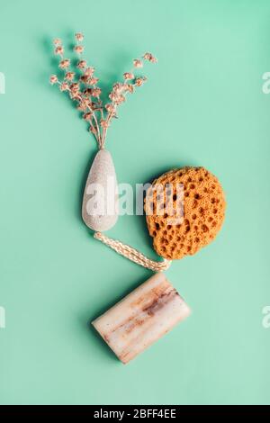 Natürliche Spa- und Hautpflegeprodukte mit Badezubehör, darunter Naturschwamm, Bimsstein und Peeling-Seife mit trockenen Kräutern. Flaches Lay-Muster. Stockfoto