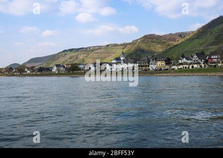 Dorf am Rhein in Deutschland mit Weinbergen am Berg im Hintergrund. Stockfoto