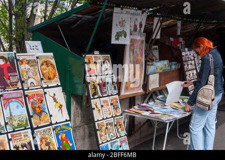 Frau mit orangefarbenen Haaren beim Stöbern in den Bouquinistes von Paris (Pariser Bücherstände), am linken Ufer der seine in Paris - Genenale Szenen von paris Stockfoto