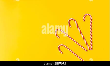 Rote Zuckerrohr auf gelbem Hintergrund. Neujahr und Weihnachten am Strand auf dem Meer. Weihnachten launisch Hintergrund. Kopierbereich. Weihnachten und Neujahr im Sommer. Stockfoto