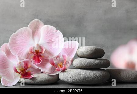 Spa Steine und rosa Orchidee auf dem grauen Hintergrund. Spa-Konzept. Stockfoto