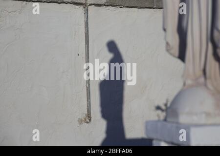 Schatten auf einer alten Wand einer Statue der Madonna Stockfoto