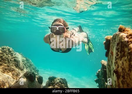 Eine schöne junge Frau hat Spaß im Sommerurlaub erkunden Meeresboden während Tauchen im Meer. Stockfoto