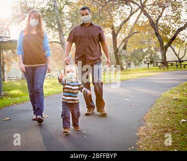Glücklich Gemischte Rasse Ethnische Familie Zu Fuß Im Park Trägt Medizinische Gesichtsmaske. Stockfoto