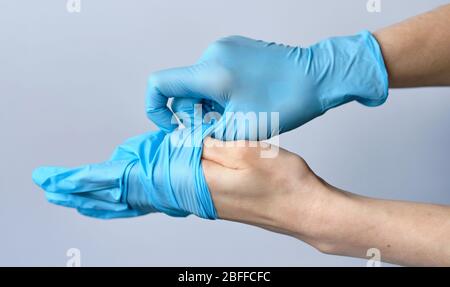 Ein Mann zieht medizinische Handschuhe aus seinen Händen. Nahaufnahme. Stockfoto