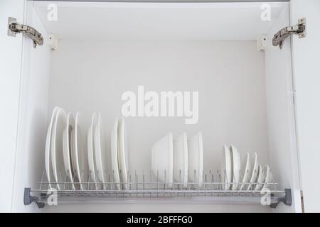 Geschirr trocknende Metallablage mit großen schönen weißen sauberen Geschirr. Traditionelle Wandschrank Küche. Stockfoto