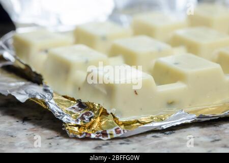 Weiße Schokolade Block Nahaufnahme. Das Paket hat eine geöffnete Aluminiumfolie. Stockfoto