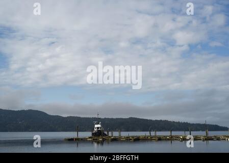 Ein Boot wird an einem Dock im Wasser des Sooke Basin an einem sonnigen April Frühlingsmorgen in Sooke auf Vancouver Island in British, Columbia, Kanada, festgebunden Stockfoto