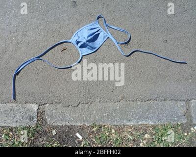 Medizinische Gesichtsmaske Wegwerfen lassen achtlos auf dem Weg von fahrlässigen Menschen. Wirkung von Coronavirus.verwendete Gesichtsmasken in der Straße übersät. Stockfoto