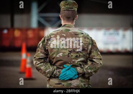 Bronx, Vereinigte Staaten Von Amerika . April 2020. Ein Soldat der US-Armee wartet am 18. April 2020 auf den nächsten Taxifahrer an der Kingsbridge Armory in der Bronx. Die Waffenarsenal wird während der COVID-19-Krise als temporäres Lebensmittelverteilzentrum genutzt und Soldaten der US-Armee laden Mahlzeiten in die Kabinen von TLC-lizenzierten Fahrern, die sie während der COVID-19-Pandemie an die in Not gereteten New Yorker liefern. (Foto Gabriele Holtermann-Gorden/Sipa USA) Quelle: SIPA USA/Alamy Live News Stockfoto