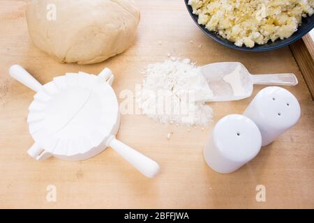 Nationale russische Küche. Pierogi oder Pyrohy, Vareniki, serviert mit Quark und Kartoffeln an Bord. Rohe Knödel aus Teig in handgefertigtem flou Stockfoto