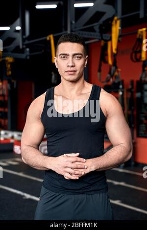 Sportlicher Lifestyle. Junger Mann, der im Fitnessstudio steht und selbstbewusst lächelt Stockfoto