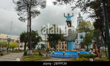 Cayambe, Pichincha / Ecuador - Februar 24 2020: Menschen sitzen im zentralen Park der Stadt mit der Matriz-Kirche im Hintergrund Stockfoto