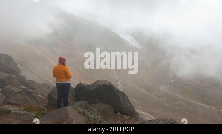 Cayambe, Pichincha / Ecuador - Februar 24 2020: Allein junge Frau, die die Landschaft des Cayambe Vulkans in der Nähe der Ruales Oleas Berge betrachtet Stockfoto