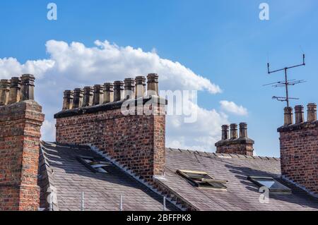 Reihen von Schornsteinen auf Backstein gebaut Schornsteine auf einem Schieferdach mit TV-Arial. Stockfoto