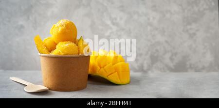 Erfrischendes Mango-Eis in Craft Pappbecher auf Grau Hintergrund Stockfoto
