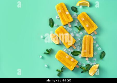 Draufsicht auf hausgemachte vegane Mango-Popsicles auf trendigem Aqua menthe Hintergrund Stockfoto