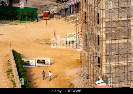 Im Bau ein mehrstöckiges Gebäude mit verrosteten Gerüsten und einem leeren Feldweg an der Seite Stockfoto