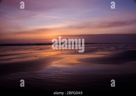 Lila und Orange Sonnenuntergang im Cefn Sidan Beach Pembrey Country Park, South Wales. GROSSBRITANNIEN Stockfoto