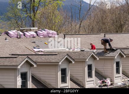 Morgantown, WV - 18. April 2020: Dachdecker ersetzen die alten Schindeln auf einem Stadthaus Dach Stockfoto