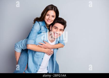 Portrait of positive leidenschaftliche Student Ehegatten genießen Zweisamkeit Wochenende Umarmung Huckepack tragen Jeans lässig Stil Outfit isoliert über graue Farbe Stockfoto