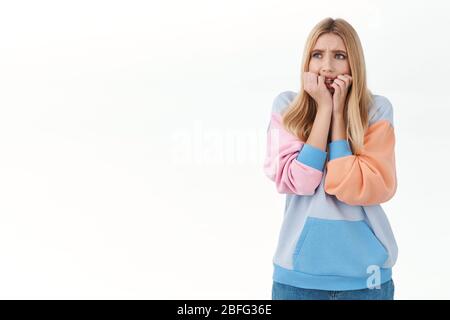 Angst blonde unsichere Mädchen fühlen sich unsicher, zitternde Angst, beißen Nägel und schaukig weg erschrocken, hören gruseligen Lärm, stehen erschrocken und entsetzt Stockfoto