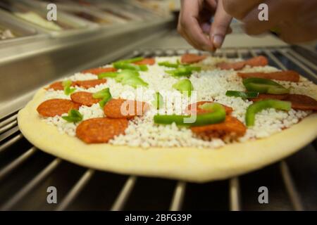 Ein Domino Pizza Mitarbeiter vorbereiten eine frische Pizza Kochen Ofen betriebsbereit. Stockfoto