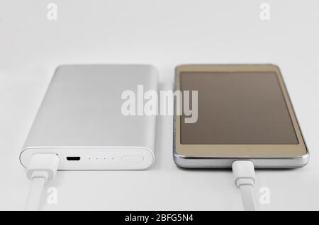 Nahaufnahme des externen Akkus, der ein Mobiltelefon lädt. Powerbank Stromspeicher . Stockfoto
