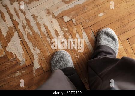 Füße in Wollgestricksocken, auf einem alten, schäbigen Parkett. Kopierbereich. Stockfoto