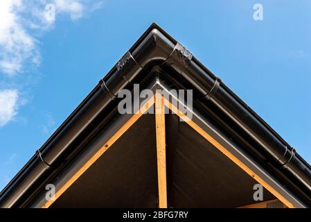 Das Dach eines Einfamilienhauses mit einer neuen Keramikfliesen in anthrazit gegen den blauen Himmel bedeckt, sichtbare Dachstühle. Stockfoto