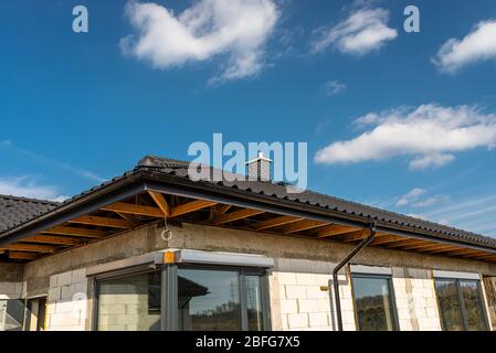 Das Dach eines Einfamilienhauses mit einer neuen Keramikfliesen in anthrazit gegen den blauen Himmel bedeckt, sichtbare Dachstühle. Stockfoto