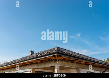 Das Dach eines Einfamilienhauses mit einer neuen Keramikfliesen in anthrazit gegen den blauen Himmel bedeckt, sichtbare Dachstühle. Stockfoto