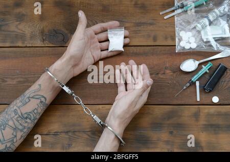 Drogenhändler wurden zusammen mit ihrem Heroin verhaftet. Die Polizei verhaftete den Drogenhändler mit Handschellen. Gesetz und Polizei Konzept für Welt Anti-Drogen-Tag. 26 J Stockfoto