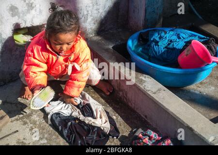 Armes junges weibliches Kind, das in Armut lebt. Arbeit in jungen Jahren und Wäsche waschen in Chomrong Nepal Mountain Village Stockfoto