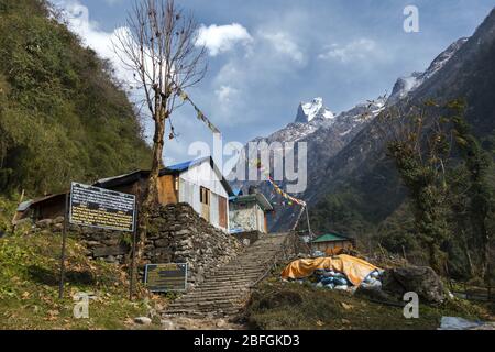 Mountain Village House und Trekking Information Schild auf Annapurna Base Camp Sanctuary Wanderung. Machapuchare Mountain Peak Nepal Himalaya Mountains Stockfoto