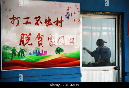 Rizhao, Chinas Provinz Shandong. April 2020. Ein Poster mit der Aufschrift "Holen Sie sich einen bezahlten Job in der Heimatstadt, befreien Sie sich in naher Zukunft von der Armut" wird an einer Wand eines Workshops zur Armutsbekämpfung im Dorf Zhongjiayaqian in der Gemeinde Shichang des Bezirks Wulian, Ostchinesische Provinz Shandong, 17. April 2020 aufgehängt. Im Laufe der Jahre hat die Grafschaft die Entwicklung verschiedener Industrien zur Armutsbekämpfung gefördert, darunter Kirschpflanzungen, Photovoltaikerzeugung und Gastfamilien-Tourismus, mit dem Ziel, den Armen vor Ort zu helfen, die Einkommen zu verbessern und die Armut abzubauen. Kredit: Wang Kai/Xinhua/Alamy Live News Stockfoto